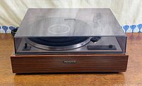 Turntable with dust cover closed showing wood plinth and Pioneer badge