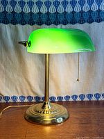 Front view of lamp showing green shade, brass base and pull chain