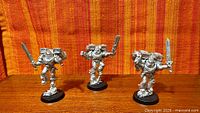 Front view of three unpainted metal Vanguard Veteran miniatures on bases