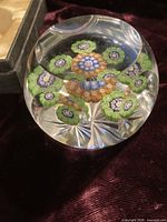angled view of faceted millefiori paperweight highlighting cane pattern and star-cut base