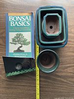 Front of book alongside stacked ceramic pots and kenzan in case