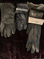 Three pairs of leather gloves laid out side-by-side on dark fabric