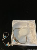 Bracelet and ring set displayed flat, showing chain connection and turquoise stones