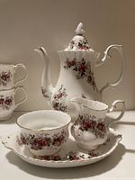 Full view of coffee pot, creamer, sugar bowl on tray with one cup in foreground