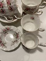 Group of tea cups, saucers, fluted dish showing pattern and gold trim