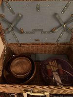 Open wicker picnic case showing bowls and utensils inside blue fabric-lined lid