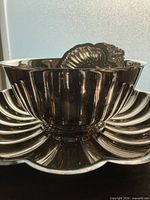 Fluted bowl resting inside large shell platter with small shell dishes visible