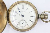 Dial side of American Waltham pocket watch showing Roman numerals, subsidiary seconds, blued hands and worn case rim