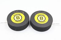 Top view of both pucks showing Boston Bruins logos and gold autographs