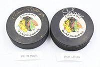 Front view of both autographed pucks showing signatures and Blackhawks logos