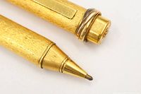 Close-up of pen tip, textured barrel, pocket clip, and decorative ring at cap showing gold-plated finish and wear
