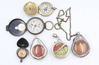 Front view of all eight items showing compasses open and teardrop cases front