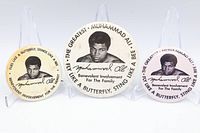 Front view of three Muhammad Ali pinback buttons showing designs and sizes