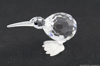 Faceted clear crystal bird figurine side profile on black background