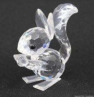 Front-left view of faceted clear crystal squirrel figurine showing body, head, ears, tail and black eyes