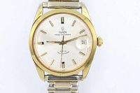 Front view showing Tudor dial, gold-plated bezel, date window, expansion bracelet