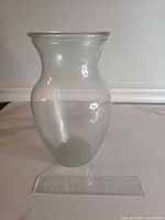 Front view of clear glass hourglass vase with ruler for scale