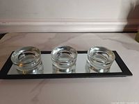 Three glass tealight holders on mirrored tray