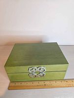 Closed green wooden jewelry box front view with clasp and ruler for scale