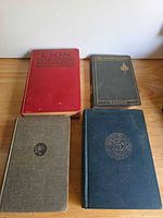 Four cloth-bound books laid flat showing front covers