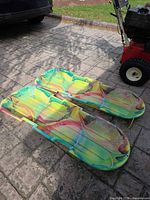 Two tie-dye plastic sleds side by side on driveway