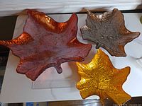 Three leaf-shaped glass bowls grouped showing colors and sizes with ruler for scale