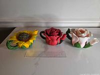 Front view of all three flower-shaped holders showing colours, shape and scale against ruler