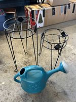 Two metal plant stands and teal watering can