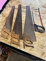 Three carpenter saws and one hacksaw on workbench