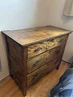 Front and top view of the wooden dresser showing three drawers, metal pulls, top surface and overall wear