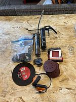 Lot overview with grease guns, cut-off wheel, abrasive discs, wire brush and hearing protector