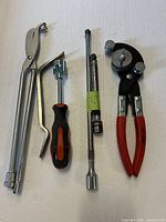 All tools laid out: pliers, spoon, screwdriver, socket extensions, tube bender