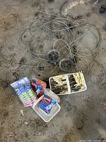 Coiled metal clothesline cable, loose pulleys, trays with wooden clothespins, two sealed packs plastic clothespins