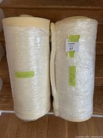 Two rolled cream foam sheets wrapped in plastic with dimension labels visible