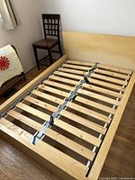 Assembled light wood IKEA bed frame showing slatted base and headboard