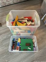 Two clear storage bins showing LEGO pieces and wooden blocks