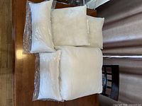 Five white pillow forms/pillows on table