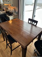 Counter-height wooden dining table, chairs partially visible
