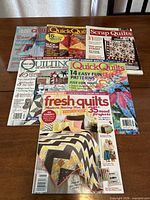 First group of six quilting magazines on tabletop
