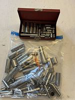 Open red metal box with sockets and sealed bag of additional sockets