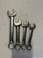 Four Snap-on stubby combination wrenches laid out showing open and box ends, size stamps visible