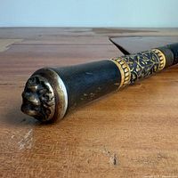 Side view showing carved floral band and brass twist lock on ebonized cane