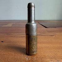 Front view of closed brass and steel bullet corkscrew standing upright showing inscription