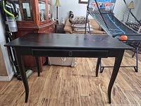 Full view of black distressed wood desk with cabriole legs and drawer