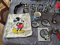 Tote bag, four tumblers, mug, coasters, part of travel bottle and keychain group laid on table