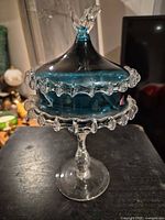 Front view of one covered compote showing stem, bowl, lid and decorative rim