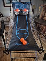 Full view of REC-TEK arcade basketball unit with two hoops, ramp, side nets and two balls on play surface