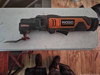 RIDGID 12V oscillating multi-tool with blade and battery attached, side profile