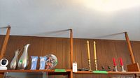Shelf view showing metal pitcher, boxed vases, collector plate on stand, candlesticks with candles
