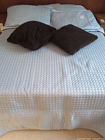 Made bed showing frame outline, bedspread, shams, throw cushions